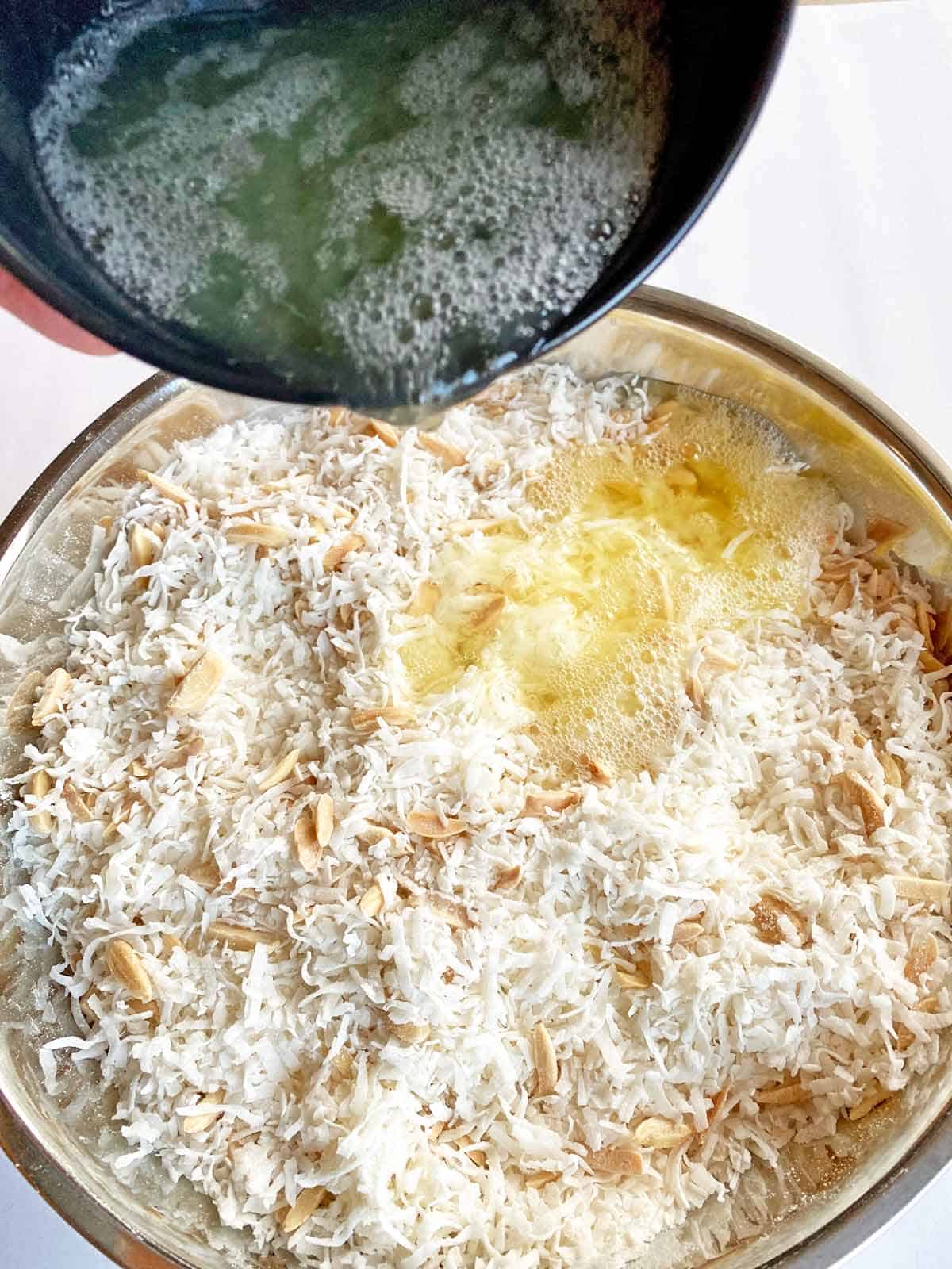 Adding egg whites to a bowl of coconut and slivered almonds.