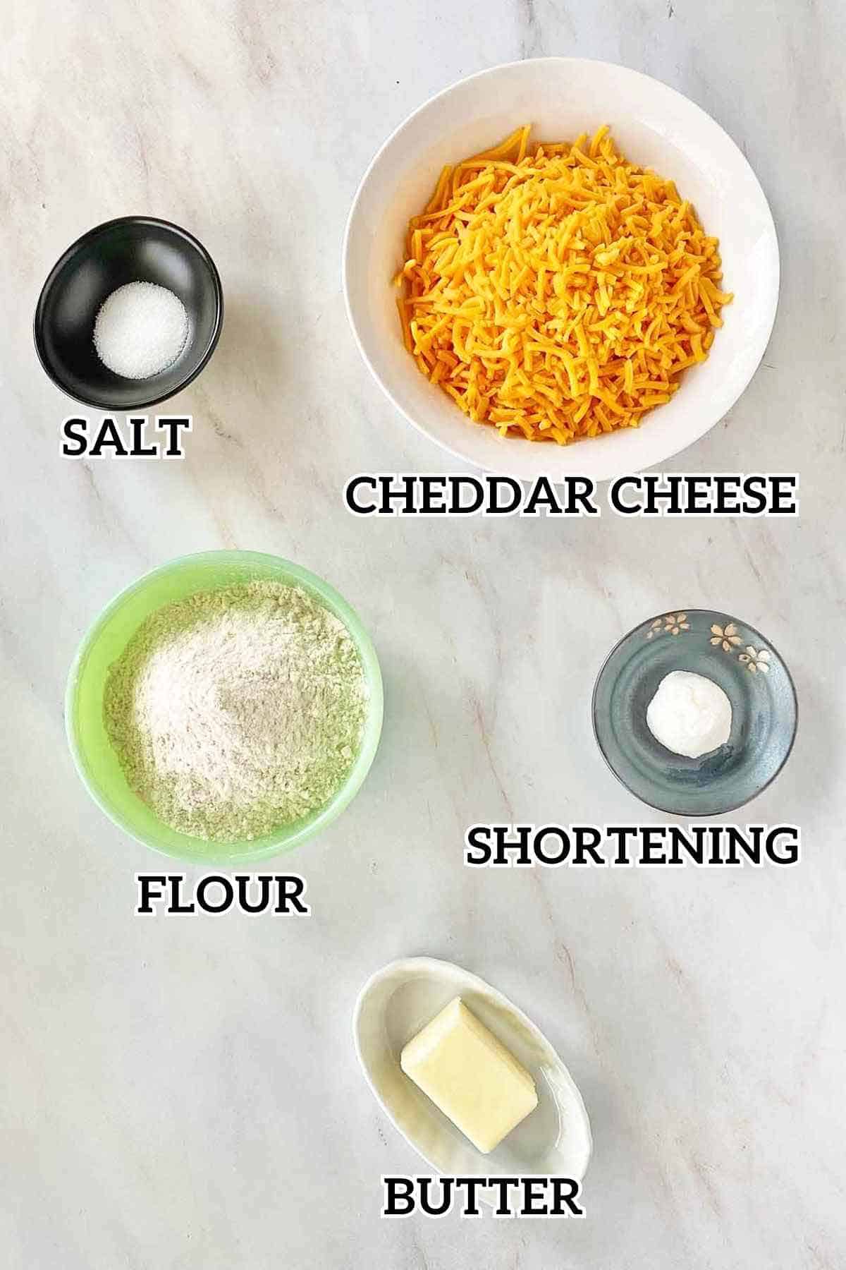 Salt, cheddar cheese, flour, shortening and butter, the ingredients to make homemade cheese crackers.