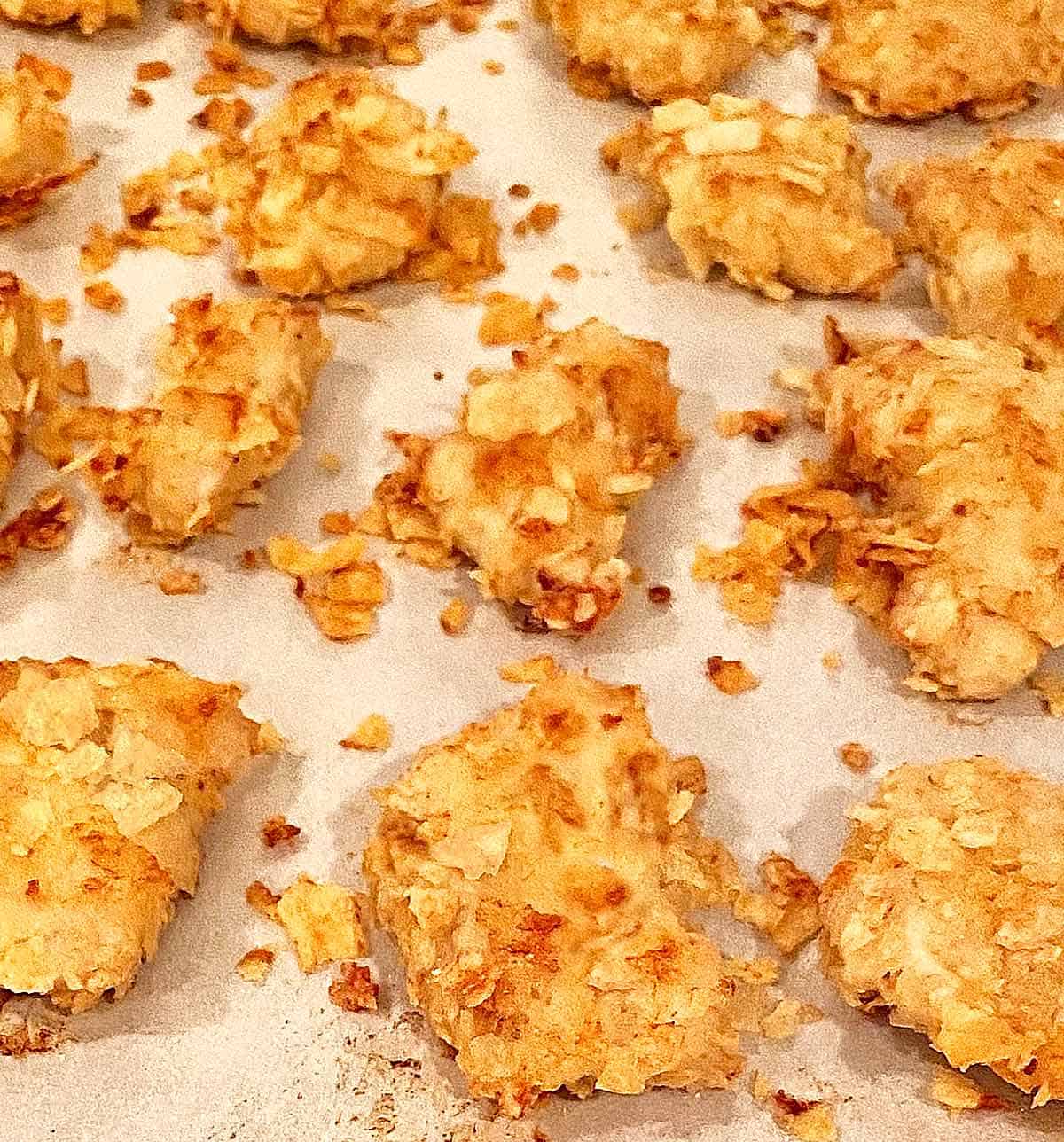 Cooked potato chip chicken strips on a baking sheet.