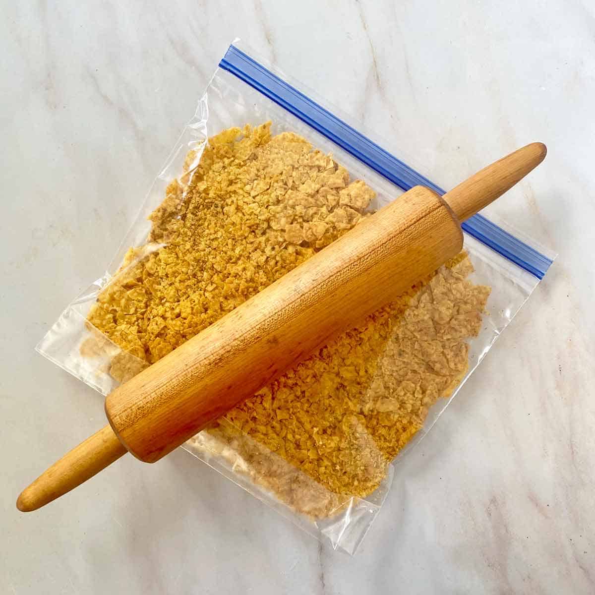 Using a rolling pin to crush cool ranch Doritos in a ziplock bag.