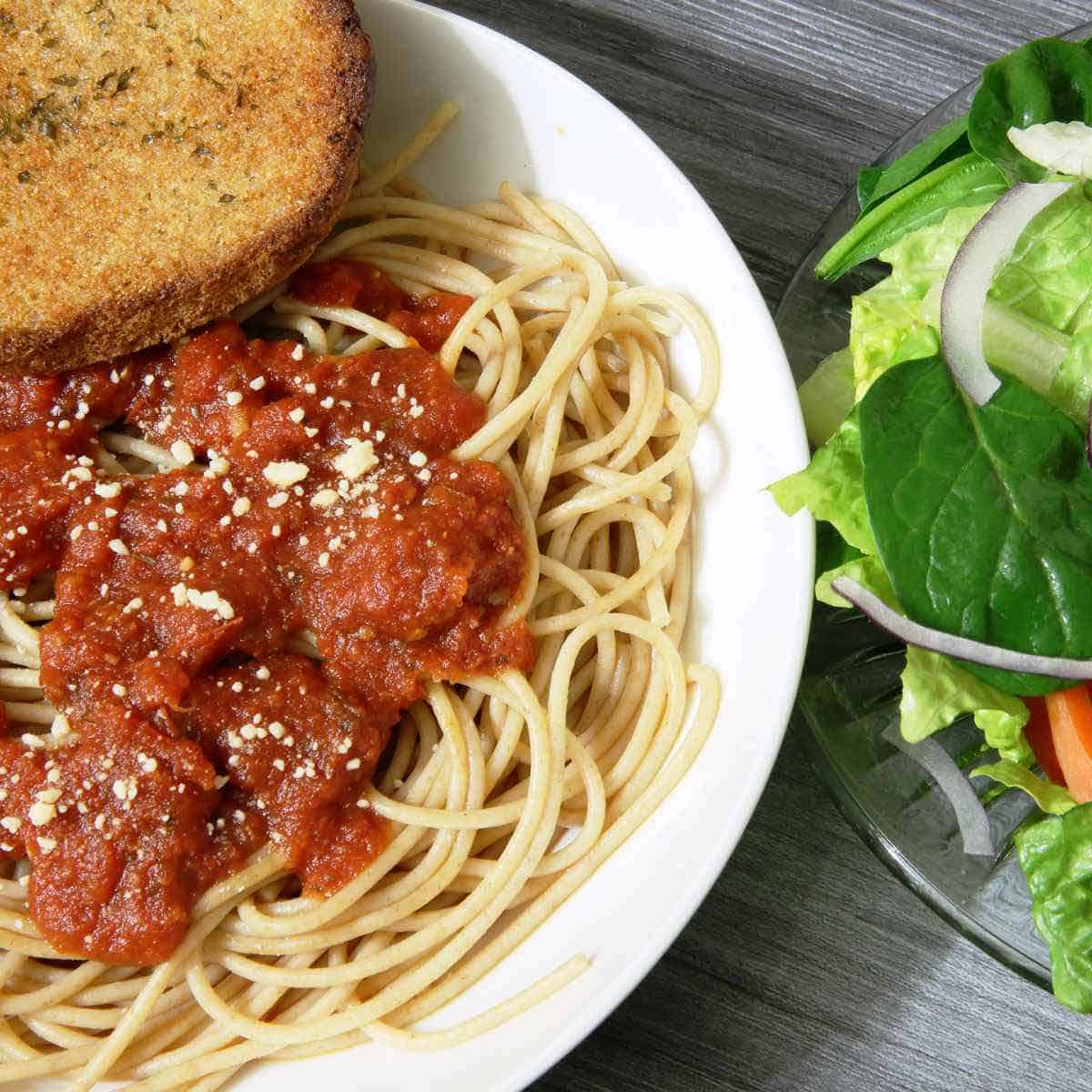 tomato A plate of spaghetti and meatballs, and a salad.