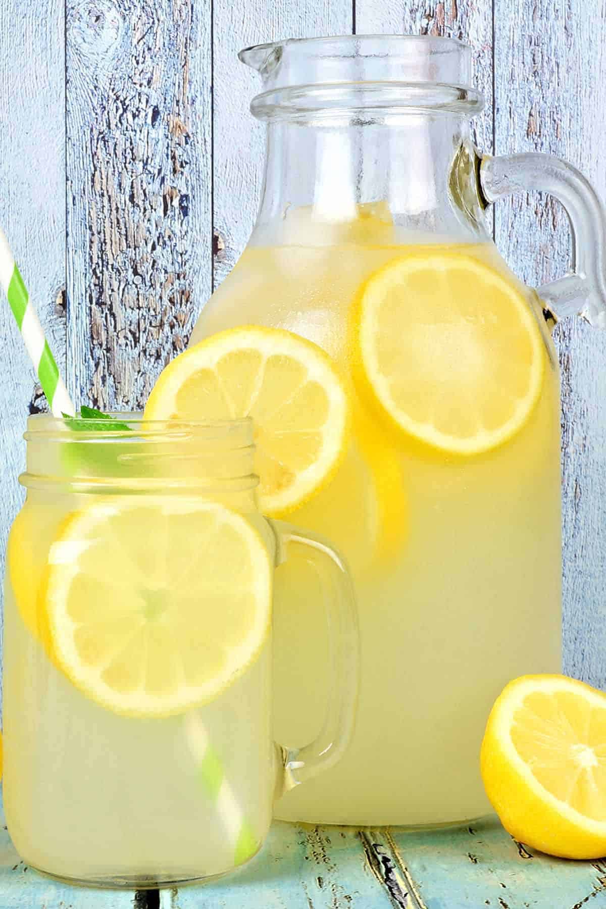 Homemade Lemonade Recipe Pitcher with two glasses of homemade lemonade and fresh lemons.