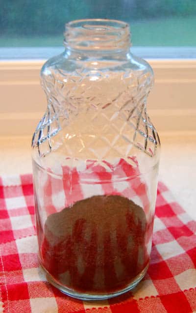 A glass bottle with ground coffee inside.