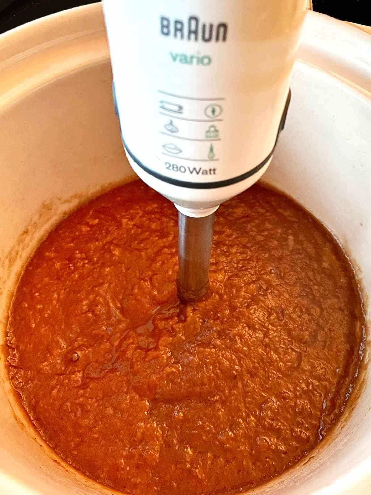 Using an immersion blender to puree the apple mixture.