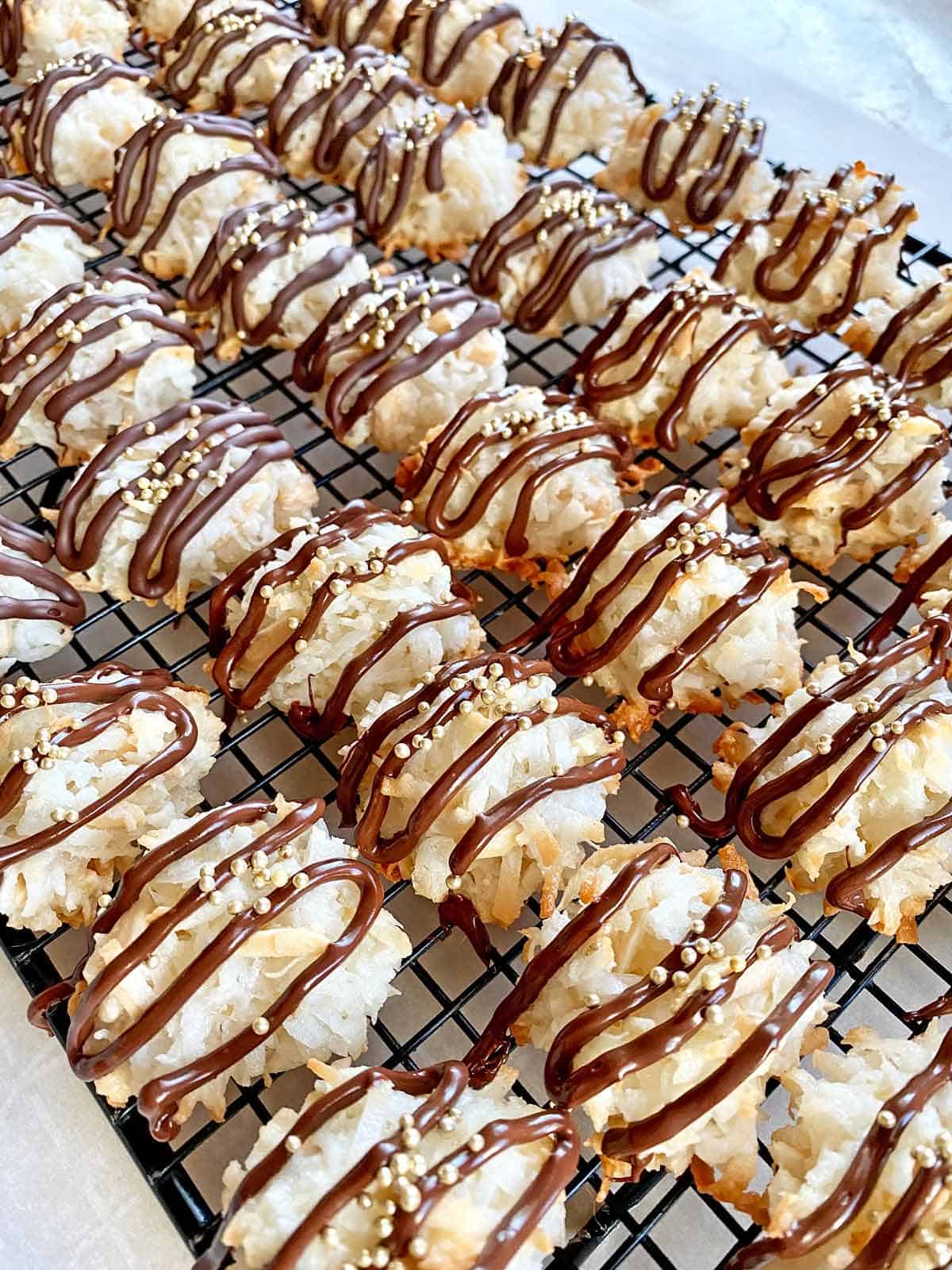 Coconut almond macaroons on a wire cooling rack, decorated with chocolate and sprinkles.