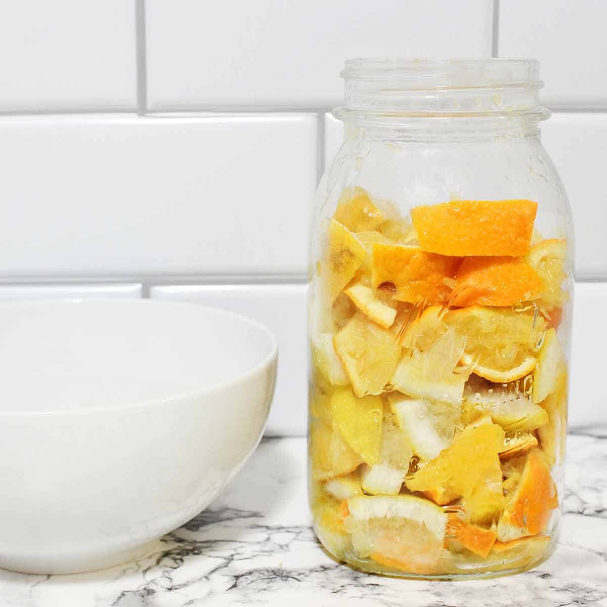 A glass Ball jar filled with orange peels and lemon peels.