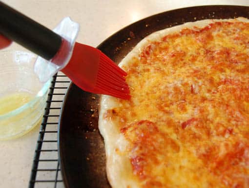 pizza10 Brushing pizza crust with garlic butter at HappySimpleLiving.com
