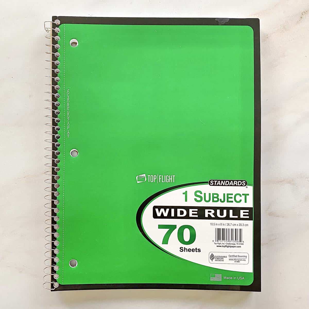 A bright green spiral notebook for writing about positive change.