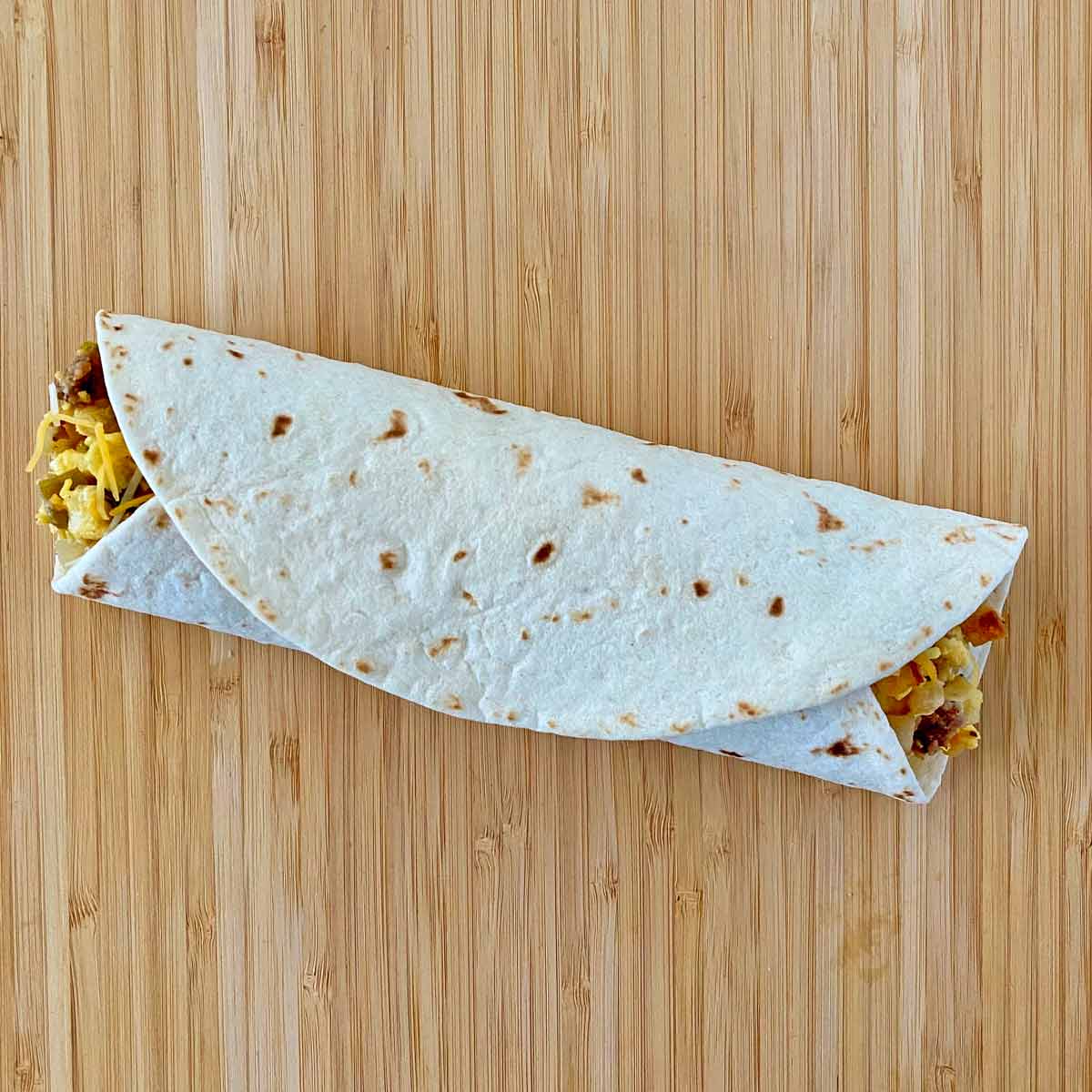burrito5 A freshly made breakfast burrito rolled on a cutting board.