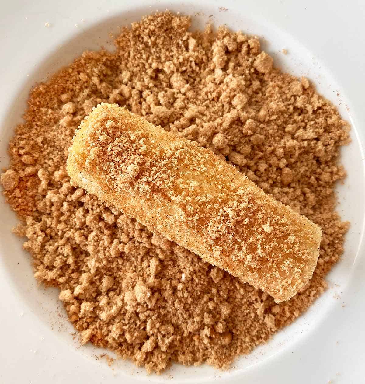 Rolling the butter coated rollup in the cinnamon sugar mixture.