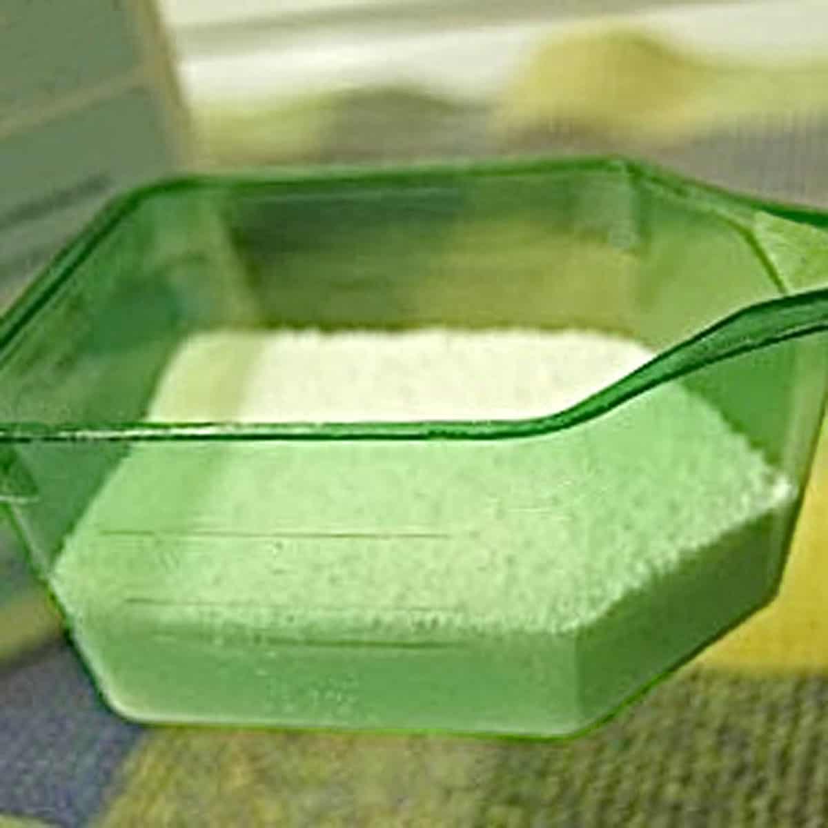 LaundrySoap A green scoop partially filled with laundry detergent.