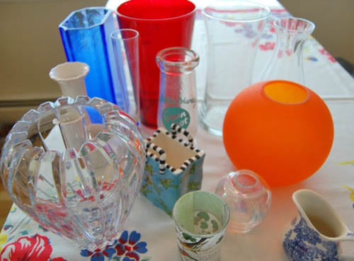 Thirteen colorful vases arranged on a table.