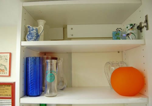 A clean cabinet space holding a dozen glass vessels.