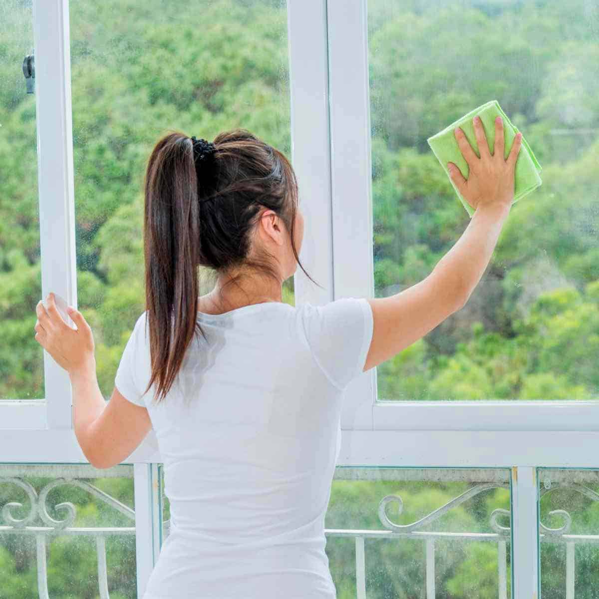 CleaningWindows A woman cleaning a window with DIY vinegar window cleaner.